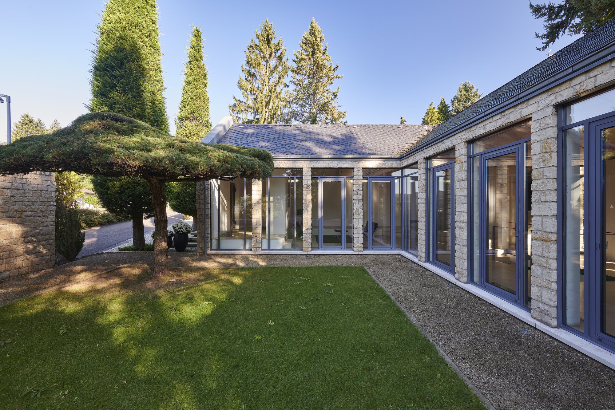 Architekturfotografie Haus S., Bliesgau — Der verglaste Flügel am Gartenplateau, links eine Schirmkiefer