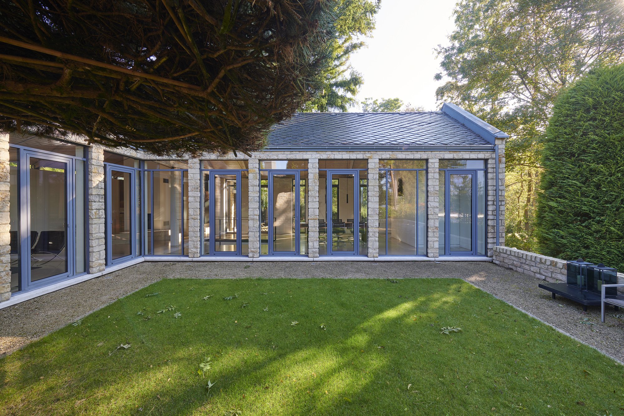 Architekturfotografie Haus S., Bliesgau — Blick über den Rasen auf die durchgehende Verglasung des Wohnflügels
