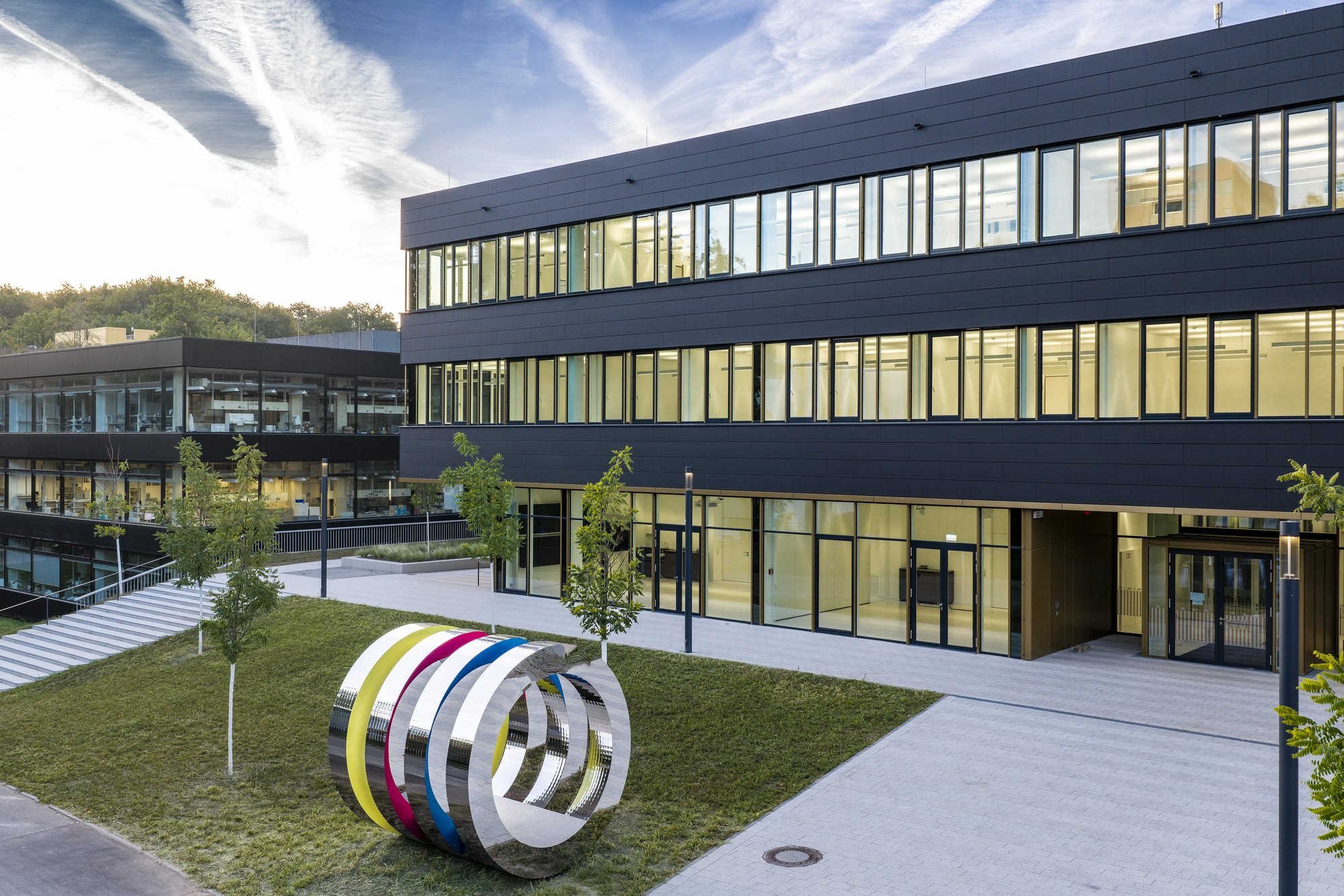 Architekturfotografie Zentrum für Biophysik ZBP, Saarbrücken — Vorplatz mit der Skulptur »PHI 42«, dahinter der Haupteingang unter dem auskragenden Obergeschoss