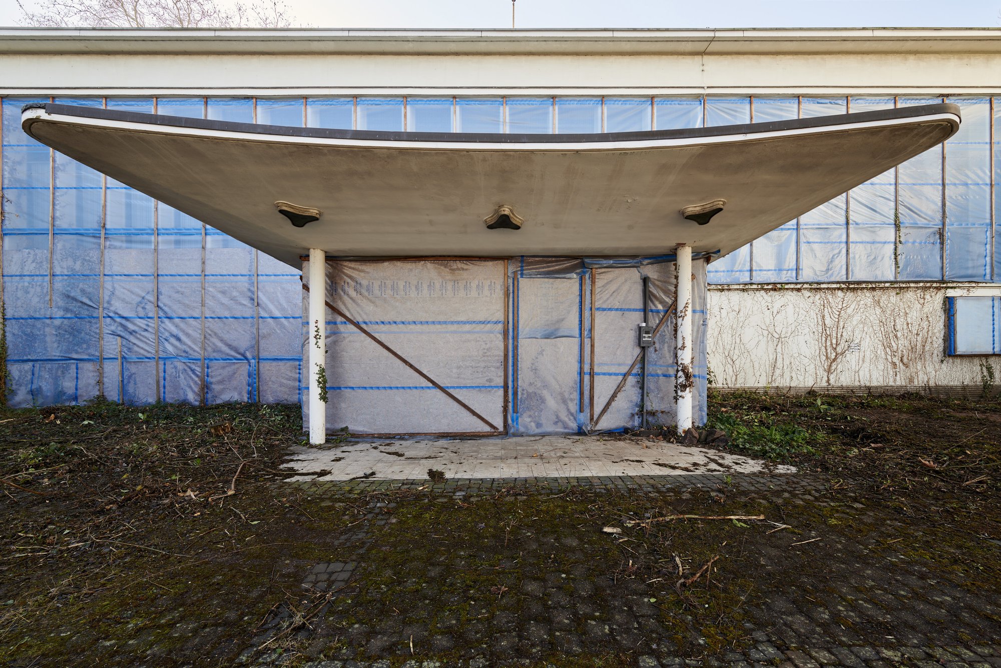 Architekturfotografie ehemalige Französische Botschaft, Saarbrücken — Die geschwungene Betonschale des Eingangsvordachs, der Eingang dahinter verhängt